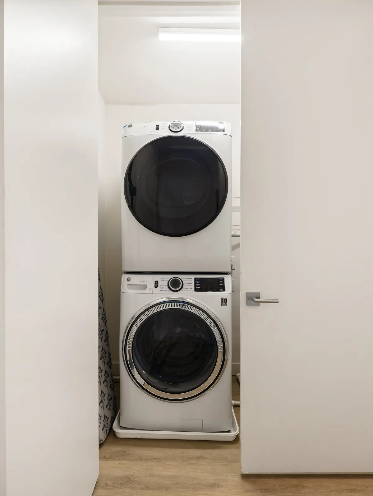 A bright laundry area featuring a stacked washer and dryer, complemented by clean white cabinetry. The space is organized and efficient, ideal for handling daily laundry tasks with ease.