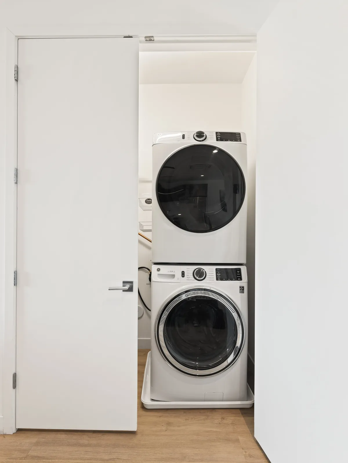 A functional laundry space with a stacked washer and dryer and white cabinetry, conveying a sense of modern utility. This area is well-lit and practical, showcasing the ease of maintaining fresh clothes during your stay.