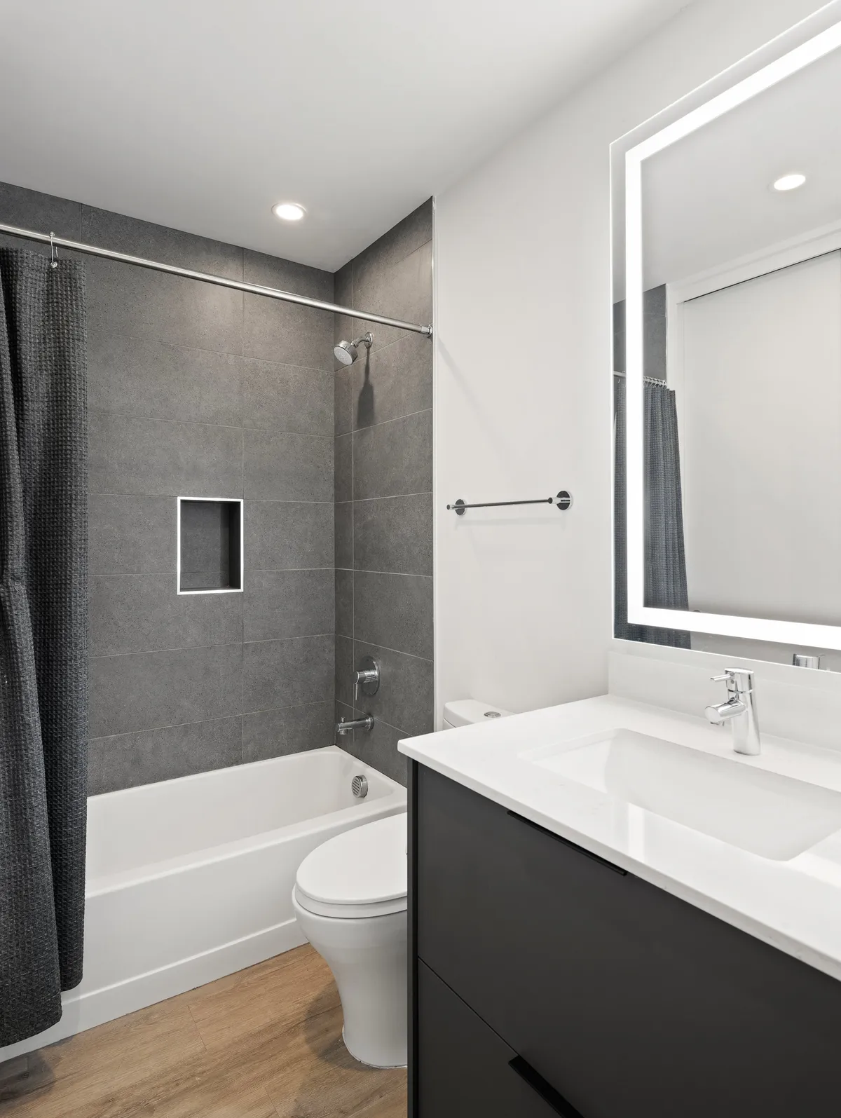 A serene ensuite bathroom with a large bathtub, sleek vanity, spacious shower area, and a broad mirror. The space is designed for ultimate relaxation and privacy, with a calm, spa-like ambiance.