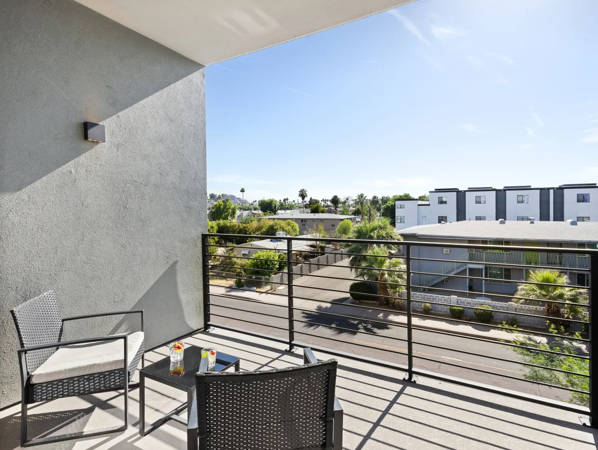 This image focuses on tranquil balcony seating with a decorative railing and a broad landscape view. The setting is ideal for reading a book, socializing with friends, or relaxing with a drink while enjoying the sunset or morning light. The scene exudes a peaceful yet connected-to-the-outside-world atmosphere.