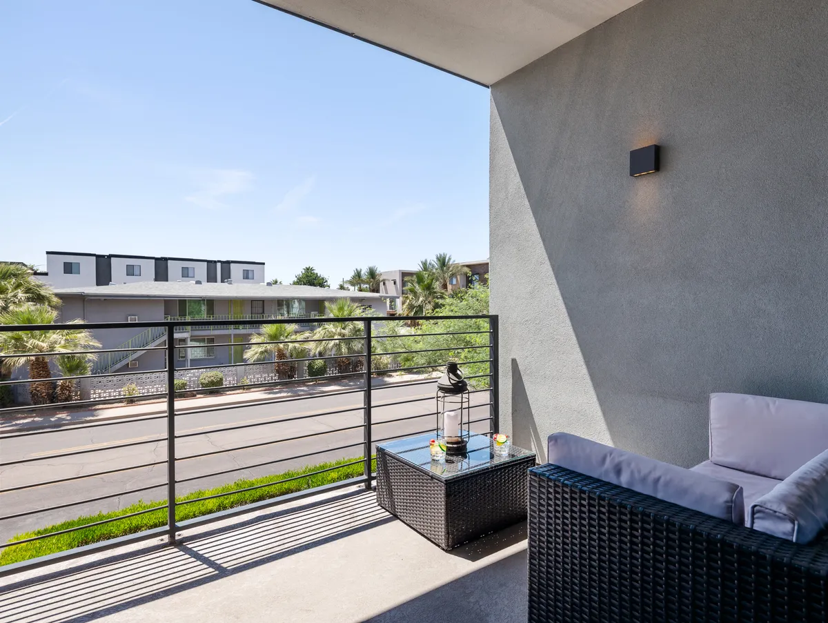 A cozy exterior balcony featuring comfortable seating, modern railings, potted plants, and a broad street view. This space is perfect for informal team conversations, morning coffee breaks, or unwinding after a day of meetings, directly connecting guests to the urban vibrancy of Old Town Scottsdale.
