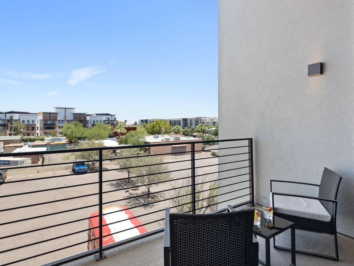 An inviting exterior balcony with cozy chairs, railings, and a charming view of the neighborhood. The scene exudes a peaceful vibe, ideal for unwinding and socializing after an exciting night out.